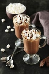 Glasses of hot chocolate with marshmallows on black background