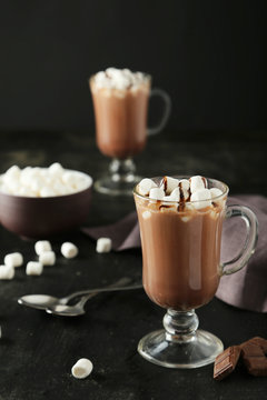 Glass of hot chocolate with marshmallows on black background