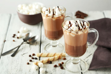 Glasses of hot chocolate with marshmallows on white wooden backg