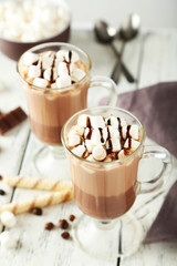 Glasses of hot chocolate with marshmallows on white wooden backg