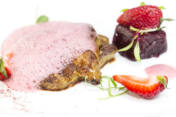 Roast goose liver is decorated with greens and strawberries