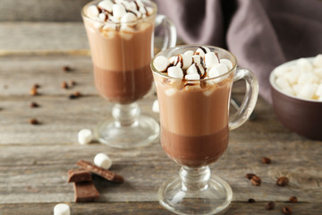 Glasses of hot chocolate with marshmallows on grey wooden backgr