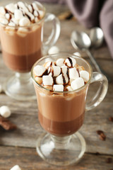 Glasses of hot chocolate with marshmallows on grey wooden backgr
