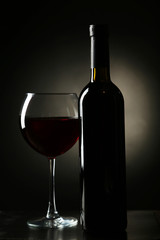 Red wine glass with bottle on black background