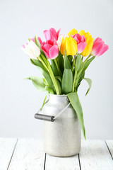 Beautiful tulips in can on white wooden background