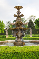 Big baroque water fountain in green chateu garden