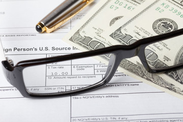 Tax form with dollar bills through glasses