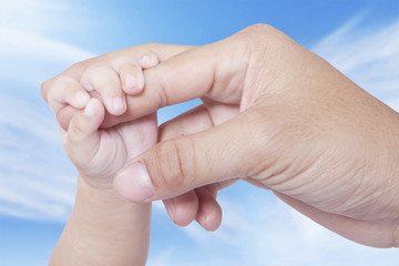 Baby hand grasping father finger