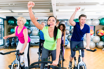 Fototapeta na wymiar Group of men and women spinning on fitness bikes in gym