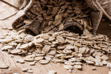 oat flakes cereal in burlap sack on wooden table.