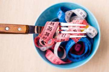 Many colorful measuring tapes in bowl on table