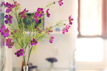 Artificial purple flowers in the well lit kitchen. 