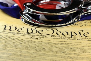 Handcuffs and American flag on US Constitution-Fourth Amendment