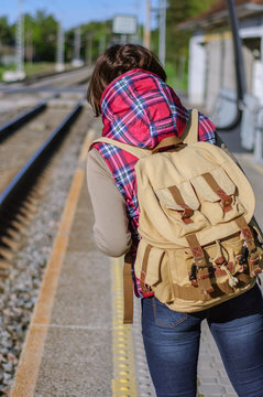 Girl with backpack waits train