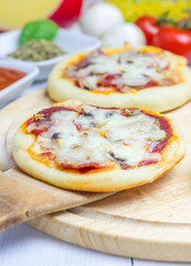 Mini pizza with salami, bacon, mushrooms and cheese