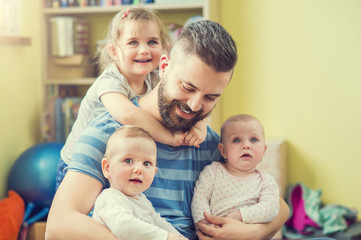 Obraz premium Young hipster father hugging his cute little daughters