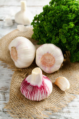 Garlic and a bunch of parsley on a white table