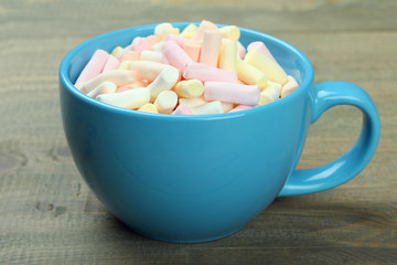 Marshmallow in a blue cup on a wooden background