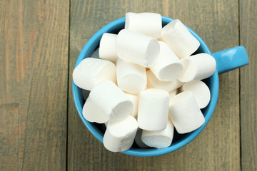 Marshmallow in a blue cup on a wooden background