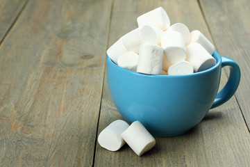 Marshmallow in a blue cup on a wooden background