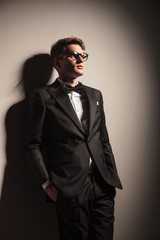 Obraz premium Handsome young business man leaning on a wall