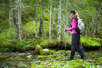 Hiker in forest crossing the stream