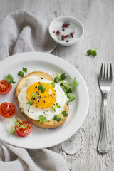 toast with egg on a white plate on a  wooden surface