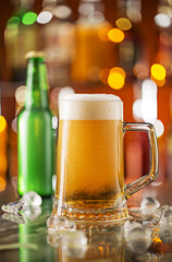 Bottle of beer with glass on bar desk