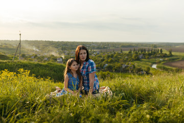 Naklejka na ściany i meble Little cute girl with her mother sitting at sunset