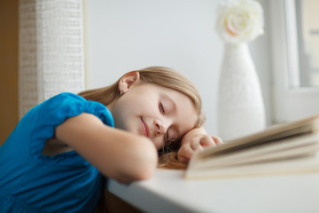 Obraz na płótnie Canvas Little girl sleeping on windowsill with book