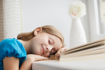 Obraz na płótnie Canvas Little girl sleeping on windowsill with book