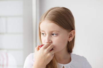 Little girl looking out the window and eating apple