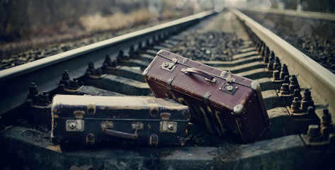 Two vintage suitcases left on railway tracks.
