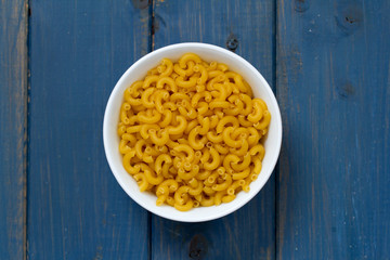 dry pasta on dish on blue background