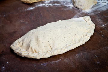 Pizza dough, spices and vegetables on wooden table.