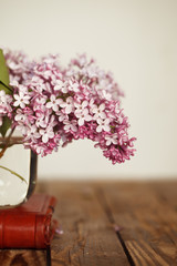 Small bouquet of lilac in glass vase  on wood background