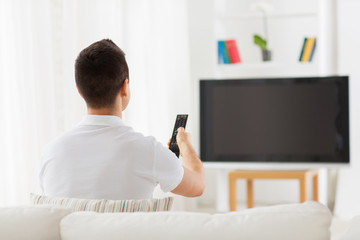 man watching tv and changing channels at home