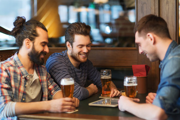 male friends with tablet pc drinking beer at bar