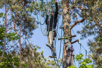 young man  climbing in adventure park, rope park 