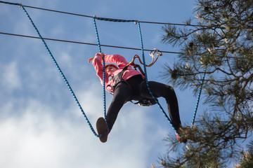 Girl climbing in adventure park , rope park  
