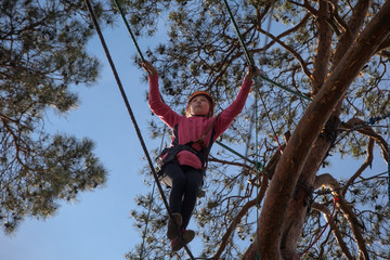 Girl climbing in adventure park , rope park  

