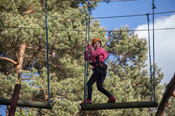 Girl climbing in adventure park , rope park  
