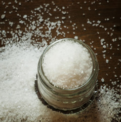 Salt in a glass jar on a wooden background, top view, selective