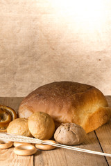 Different types of fresh bread and wheat ears on old wooden tabl