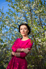 portrait of young pretty woman in pink dress posing in blooming