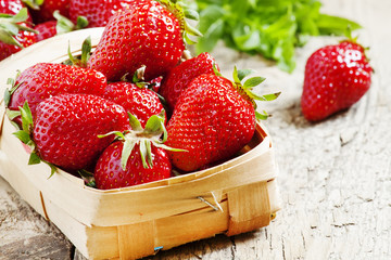 Fresh strawberries in a wicker basket on lerevyannom background,
