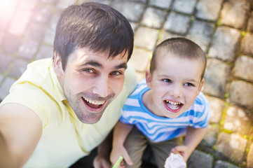 Obraz na płótnie Canvas Father and son enjoying ice cream outside in a park