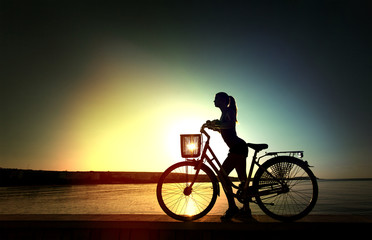 Fototapeta premium Silhouette of the beautiful streight woman with bicycle on