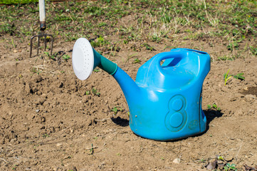 голубая пластиковая лейка стоит на земле