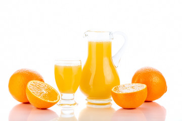 Orange juice in pitcher and oranges